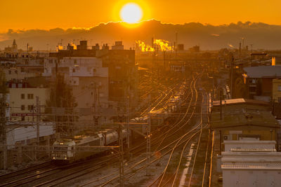 High angle view of railroad tracks by buildings in city during sunset