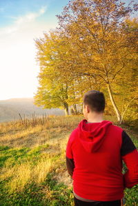 Rear view of man standing on field against sky