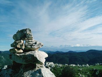 Stack of rocks against cloudy sky on sunny day