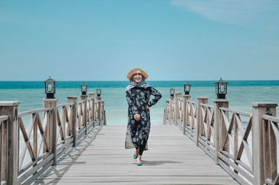 Young woman walking on footpath against sea