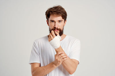 Portrait of young man standing against white background