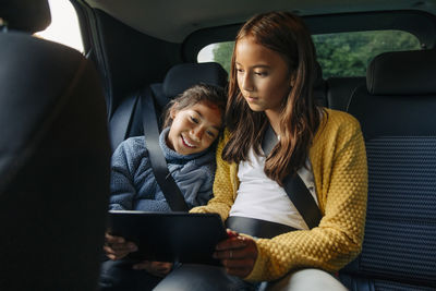 Sisters sharing tablet pc while sitting in car during road trip