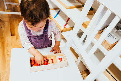 High angle view of girl playing by table in classroom