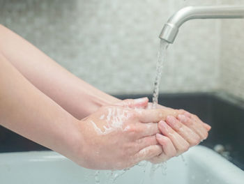 Close-up of hand touching water in bathroom