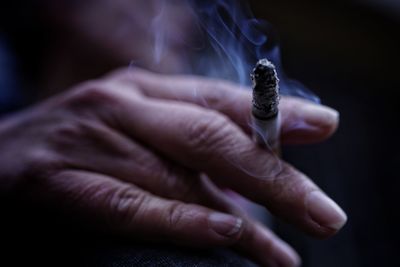 Close-up of hand holding cigarette