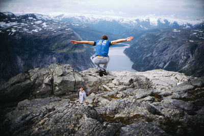 Rear view of man on rock against sky