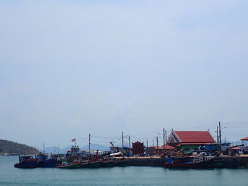 Fishing boats moored at harbor against sky