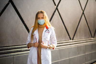 Portrait of young woman standing against wall