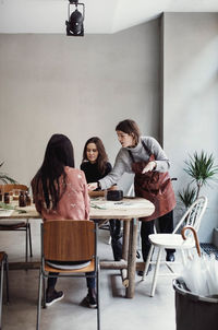 Confident female owner teaching colleagues at table in perfume workshop