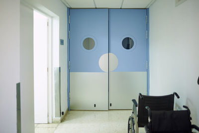 Doors in empty passage with glowing tiled floor illuminated by lamps in modern clinic