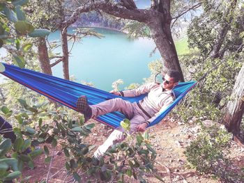 Man sitting on hammock by tree