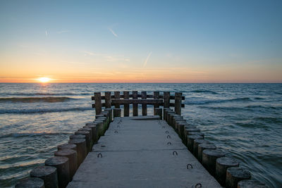 Pier over sea against sky during sunset