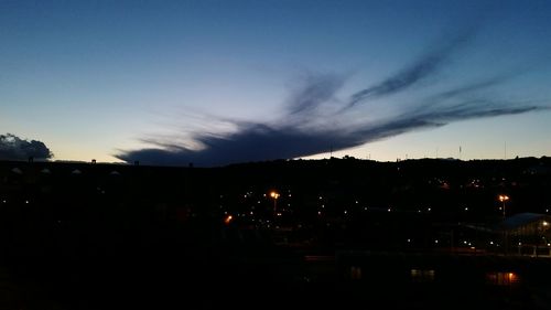 Silhouette cityscape against sky at night