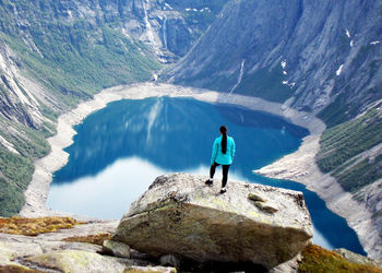 Rear view of man standing on mountain against sky