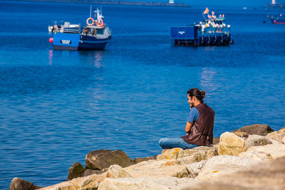 Man sitting on rock looking at sea