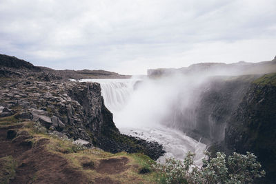 Scenic view of waterfall against sky