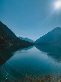 Scenic view of lake and mountains against clear blue sky