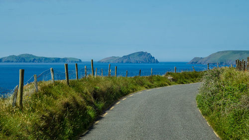 Road by sea against clear blue sky