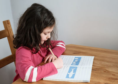 Young girl practicing her writing at the table