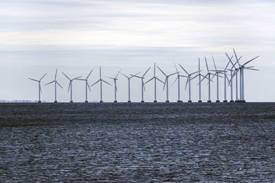 Wind turbines in sea against sky