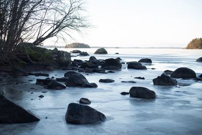 Rocks by sea against clear sky