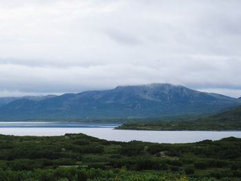 Scenic view of mountains and lake against cloudy sky