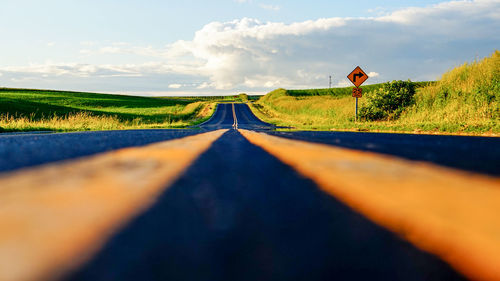 Road amidst field against sky