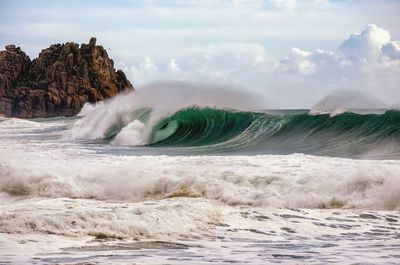 Waves rushing towards sea shore against sky