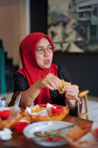 Portrait of young woman having food on table