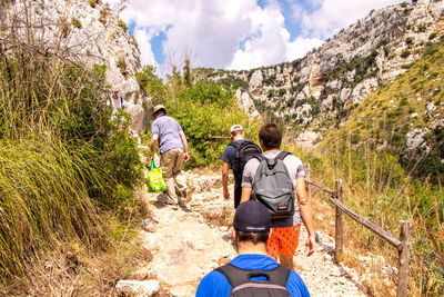 Rear view of people walking on mountain road