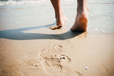 Low section of person standing on sand