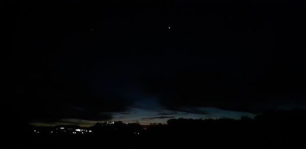 Silhouette of city against sky at night