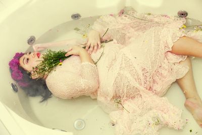 High angle view of woman wearing wedding dress lying in bathtub