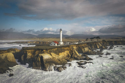 Lighthouse by sea against sky