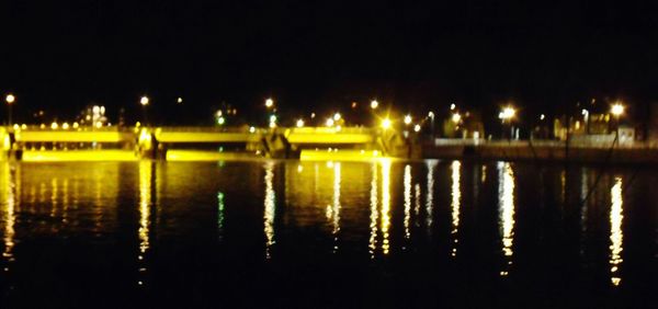 Illuminated river against sky at night
