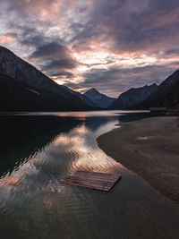 Scenic view of lake by mountains against sky during sunset