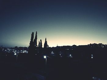 Illuminated cityscape against clear blue sky