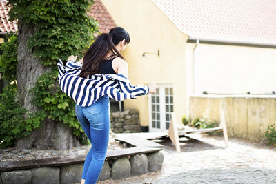 Rear view of woman standing by house