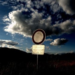 Road sign against cloudy sky