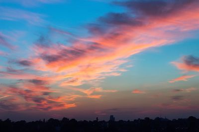 Silhouette trees against dramatic sky during sunset