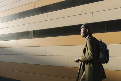 Stylish man with helmet and scooter at a building