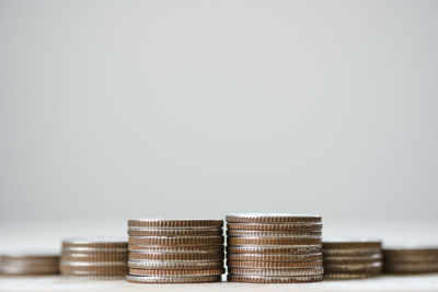 Close-up of coin stack on table against white background