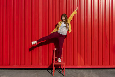 Woman standing against red wall