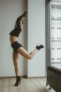 Full length of woman dancing against wall at home