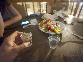 Midsection of woman holding drink on table