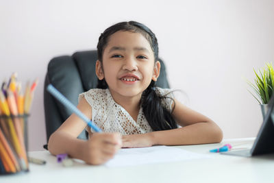 Portrait of smiling girl sitting on table