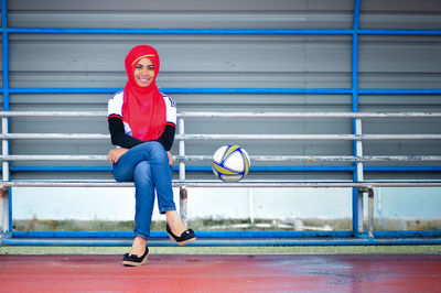 Full length portrait of young woman standing against wall