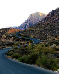 Scenic view of road by mountains against clear sky