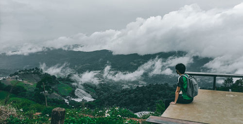 Rear view of man standing on mountain against sky