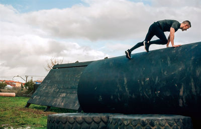 Man climbing metal against sky